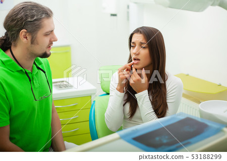 Dentist in dental office talking with female patient and preparing for treatment 53188299