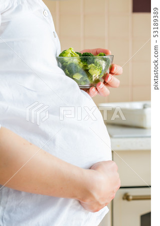 Pregnant female holding broccoli bowl Pregnant female holding broccoli bowl 53189389