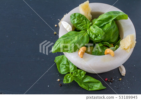 Pesto and ingredients on dark stone background Pesto and ingredients on dark stone background 53189945