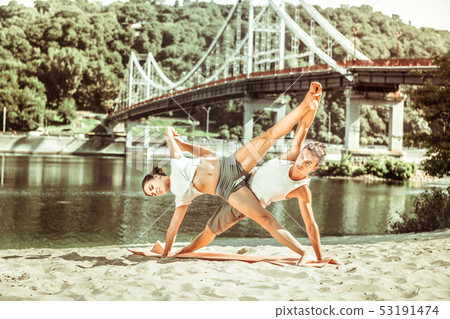 Young female and male doing acrobatic yoga exercise Young female and male doing acrobatic yoga exercise 53191474