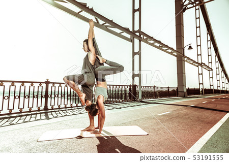 Woman doing a handstand exercise with her partner 53191555