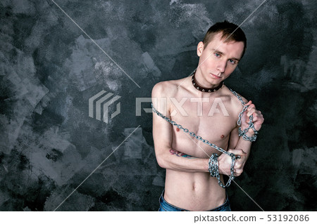 Handsome skinny guy in collar holding a chain. 53192086
