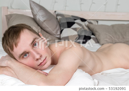 Handsome young adult man sleeping in bed. Sexy naked guy is resting 53192091