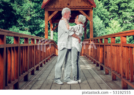 Full-sized of spouses standing on bridge and embracing each other 53192555