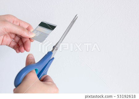 A woman cutting a credit card with blue scissors. A woman cutting a credit card with blue scissors. 53192618