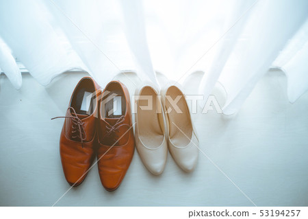 Couple's shoes are placed on ground. 53194257