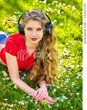 Girl in headphones catch rhythm music on green grass Girl in headphones catch rhythm music on green grass 53202354