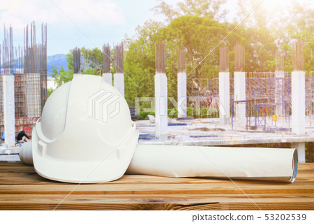 white safety hat and paper plan blueprint on wood white safety hat and paper plan blueprint on wood 53202539