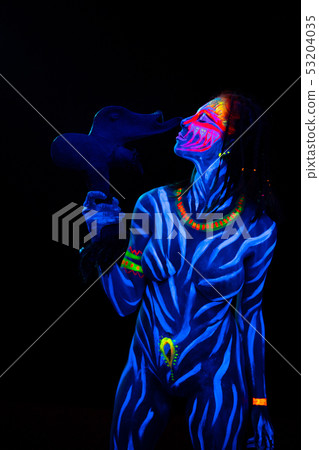 Portrait of Young naked bodyarted woman in blue glowing ultraviolet paint with tomahawk ancient Portrait of Young naked bodyarted woman in blue glowing ultraviolet paint with tomahawk ancient 53204035