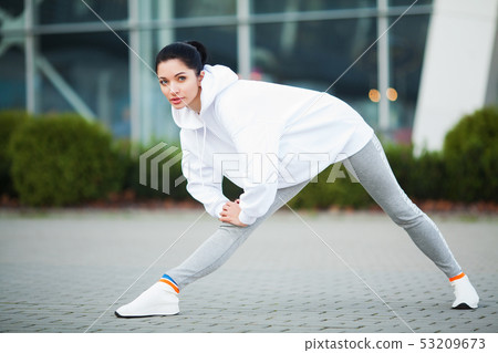Fitness girl. Young sports woman stretching in the modern city. Healthy lifestyle in the big city Fitness girl. Young sports woman stretching in the modern city. Healthy lifestyle in the big city 53209673