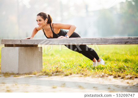 Portrait of beautiful sporty woman 20s in sportswear doing push-ups, and listening to music with 53209747