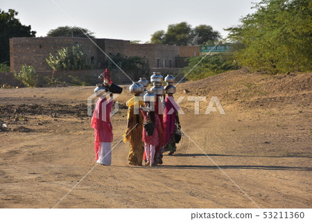 莎麗服的美麗的婦女在民間服裝，Cooley村莊，Jaisalmer，印度運載井水的圖在他們的頭 53211360