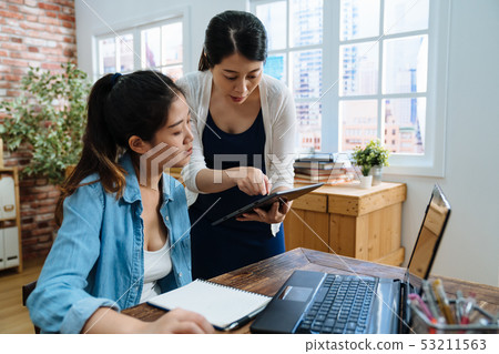seller with coworker talking point on mobile pad seller with coworker talking point on mobile pad 53211563
