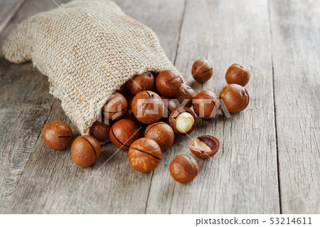 Macadamia nut on a wooden table in a bag, closeup, 53214611