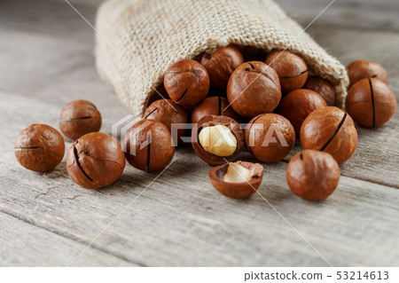 Macadamia nut on a wooden table in a bag, closeup, 53214613