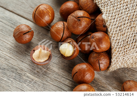 Macadamia nut on a wooden table in a bag, closeup, 53214614