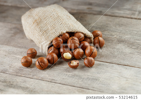 Macadamia nut on a wooden table in a bag, closeup, 53214615