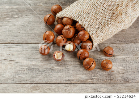 Macadamia nut on a wooden table in a bag, closeup, 53214624