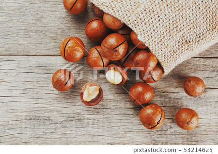 Macadamia nut on a wooden table in a bag, closeup, 53214625