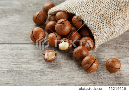 Macadamia nut on a wooden table in a bag, closeup, 53214626