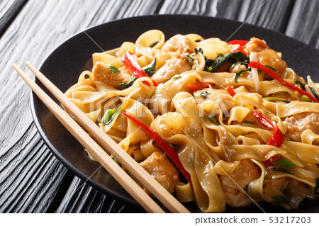 This stir-fry of wide rice noodles with chicken This stir-fry of wide rice noodles with chicken 53217203