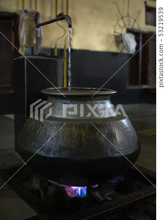 Big metal and oriental vessel stands above fire 53219539