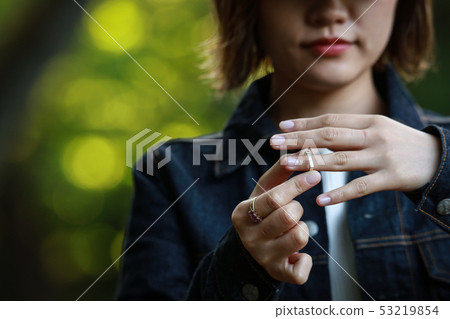 Woman removing a ring Woman removing a ring 53219854
