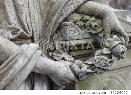 Hands holding the wreath. Old cemetery sculpture. 53224032