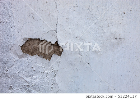 Whitewashed wall with the hole in the cracked 53224117