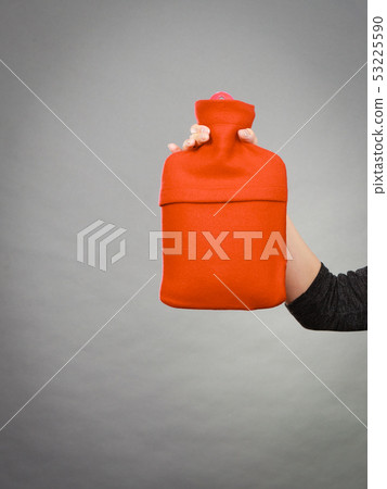 Woman holds hot water bottle in red fleece cover 53225590