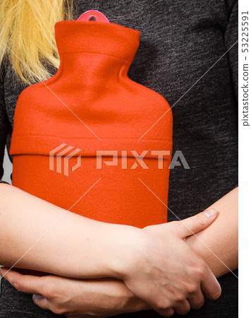 Girl having stomach ache, holding hot water bottle 53225591