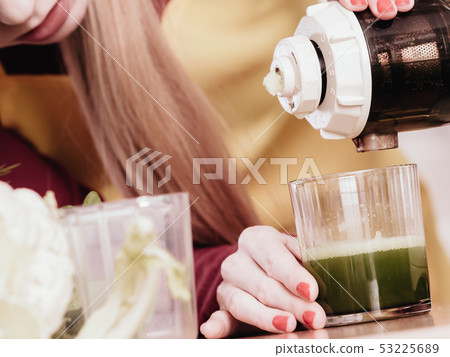 Woman in kitchen making vegetable smoothie juice Woman in kitchen making vegetable smoothie juice 53225689