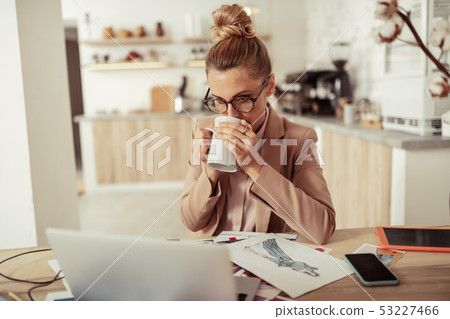 Fashion designer drinking coffee at her workplace. Fashion designer drinking coffee at her workplace. 53227466