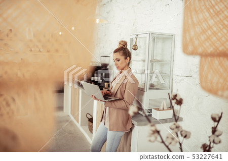 Concentrated woman working at her laptop near coffee table. Concentrated woman working at her laptop near coffee table. 53227641