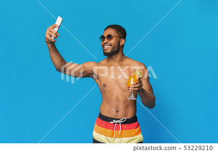 Positive black man in swimwear taking summer selfie on cellphone 53229210