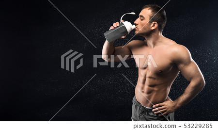 Young sporty man drinking energy cocktail in studio Young sporty man drinking energy cocktail in studio 53229285
