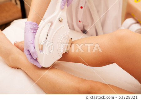 Skin Care. Hair removal on the legs, laser procedure at clinic. Beautician removes hair on beautiful Skin Care. Hair removal on the legs, laser procedure at clinic. Beautician removes hair on beautiful 53229321