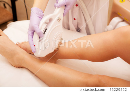 Skin Care. Hair removal on the legs, laser procedure at clinic. Beautician removes hair on beautiful Skin Care. Hair removal on the legs, laser procedure at clinic. Beautician removes hair on beautiful 53229322