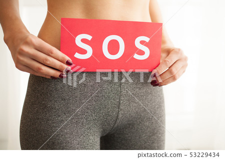 Vaginal or urinary infection and problems concept. Young woman holds paper with SOS above crotch 53229434