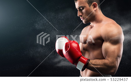 Young boxer looking on his hands in gloves and posing 53229437
