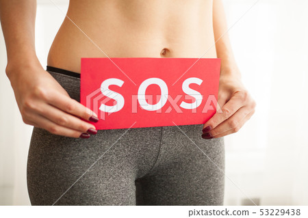 Vaginal or urinary infection and problems concept. Young woman holds paper with SOS above crotch 53229438