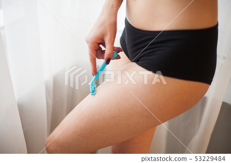 Caucasian woman shaving legs with razor at home 53229484