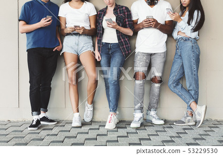 Group of diverse teenagers using cellphones outdoor Group of diverse teenagers using cellphones outdoor 53229530