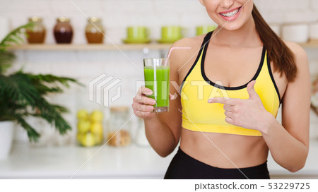 Sporty Woman Pointing On Detox Smoothie In Kitchen 53229725