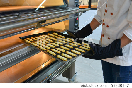 Puts cakes in the oven at bakery 53230137