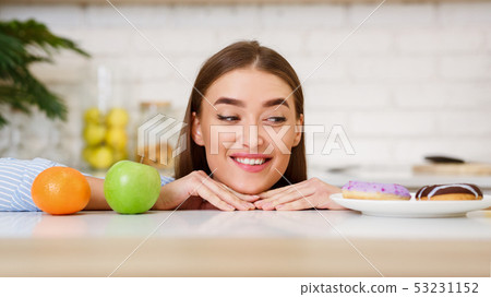 Diet And Nutrition. Woman Choosing Between Donuts And Fruits Diet And Nutrition. Woman Choosing Between Donuts And Fruits 53231152