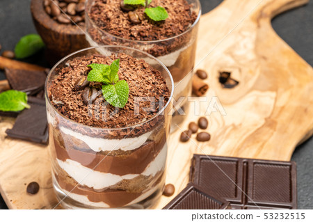 Classic tiramisu dessert in a glass on dark concrete background Classic tiramisu dessert in a glass on dark concrete background 53232515