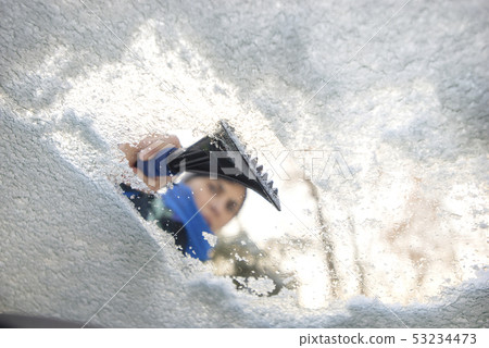 winter driving - scraping ice from a windshield 53234473