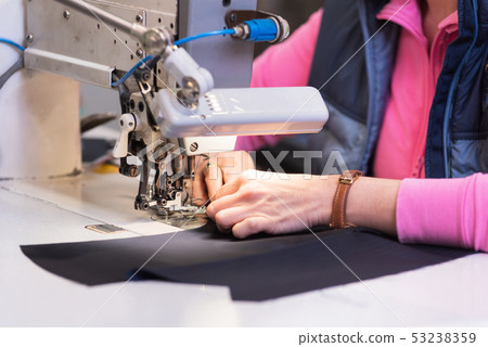 Seamstress sews clothes on a sewing machine. Textile factory. Seamstress sews clothes on a sewing machine. Textile factory. 53238359