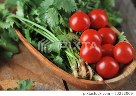 tomatoes and cilantro in a wooden plate o 53252069